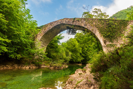 Old bridge over the Dobra river, dating from the Middle Ages and built on the remains of an old Roman road, between the municipalities of Cangas de Onis and Amieva.の写真素材