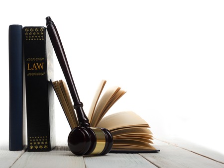 Law concept - Open law book with a wooden judges gavel on table in a courtroom or law enforcement...