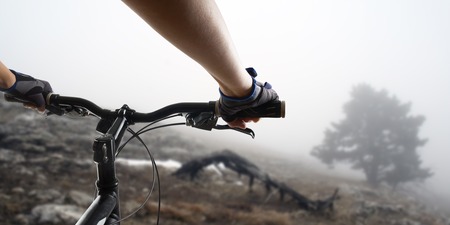 Hands in gloves holding handlebar of a bicycle. Mountain Bike cyclist riding single track. Healthy lifestyle active athlete doing sport.の写真素材