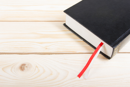 Black book with red and white bookmark on wooden table. Back to school. Copy space.の写真素材