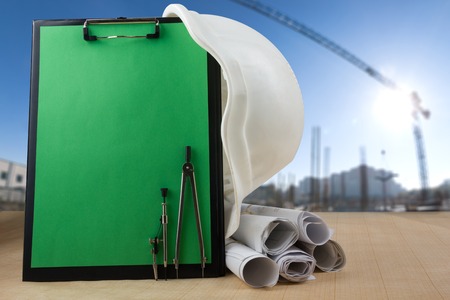 Workplace of architect - Architectural project, plan, blueprint rolls and pen, safety helmet on blank sheet of paper. Engineering tools view from the top. Construction background. Copy spaceの写真素材