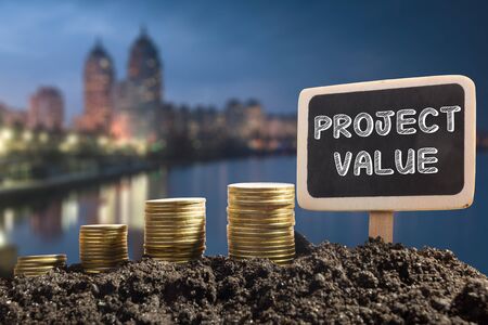 Project value - Financial opportunity concept. Golden coins in soil  Chalkboard on blurred urban backgroundの写真素材