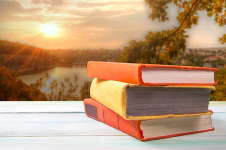 Stack of colorful books on wooden table on natural blurred background. Back to school. Copy spaceの写真素材