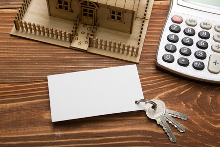 Model house, keys, blank business card, pen and calculator on wooden table Top view. Real Estate Conceptの写真素材