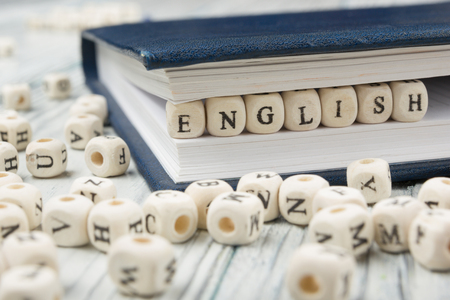 Word english made with block wood letters next to a pile of other letter over  wooden table.の写真素材