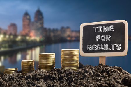 Time for results - Financial opportunity concept. Golden coins in soil Chalkboard on blurred natural backgroundの写真素材