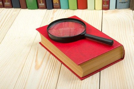 Composition with hardback book and magnifying glass on the table. Back to school, copy space. Education backgroundの写真素材