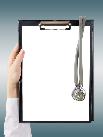 Female doctor's hand holding medical clipboard with blank sheet of paper on blie blurred background. Concept Healthcare And Medicine. Copy space.の写真素材