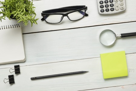Office desk table with supplies. Top view. Copy space for text. Notepad, pen, glasses, calculator, reminder and flowerの写真素材