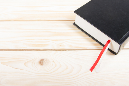 Black book with red and white bookmark on wooden table. Back to school. Copy space.の写真素材