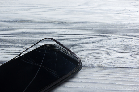 Modern broken mobile phone and money on white wooden background. Copy space. Top view.の写真素材