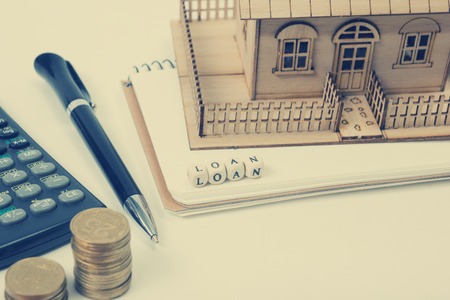 Concept of housing purchase and insurance. Office desk table with supplies top view. Calculator. golden coins, pen, notepad, green model house, wooden block with word Insurance.の写真素材