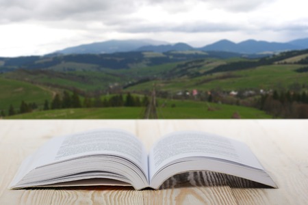 Open book on wooden table on natural blurred background.の写真素材