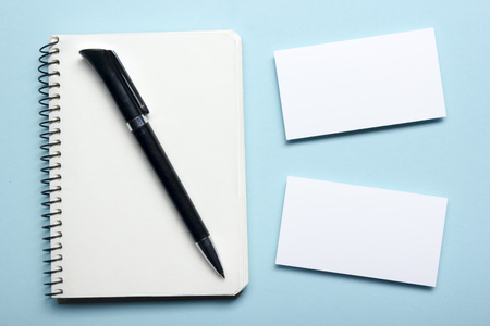 Business card blank over notepad at office table. Corporate stationery branding mock-up.の写真素材