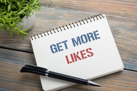 Get More Likes concept. Notebook page with text, red pencil and coffee cup. Office desk table top view.の写真素材