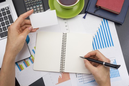 closeup of a young woman checking accounts. Office desk table with supplies top view.の写真素材
