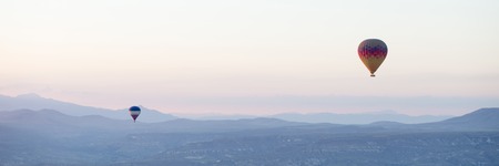 Hot air balloons over mountain landscape in Cappadocia, Goreme National Park, Turkey.の写真素材