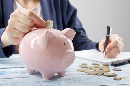 Hand putting coin into piggy bank closeup. selective focusの写真素材