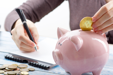 Piggy bank, hand holds golden bitcoin coin virtual money. Cryptocurrency and saving conceptの写真素材