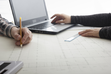 Architects working on blueprint, real estate project. Architect workplace - architectural project, blueprints, ruler, calculator, laptop and divider compass. Construction concept. Engineering tools.の写真素材