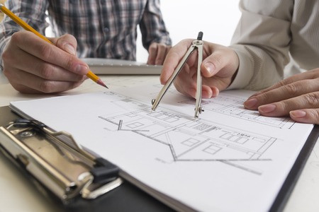 Architects working on blueprint, real estate project. Architect workplace - architectural project, blueprints, ruler, calculator, laptop and divider compass. Construction concept. Engineering tools.の写真素材