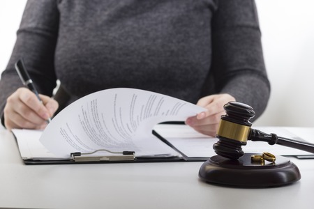 Hands of wife, husband signing decree of divorce, dissolution, canceling marriage, legal separation documents, filing divorce papers or premarital agreement prepared by lawyer. Wedding ringの写真素材