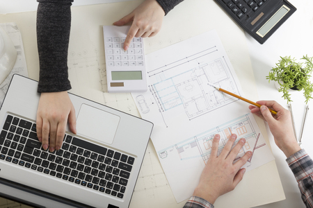 Architects working on blueprint, real estate project. Architect workplace - architectural project, blueprints, ruler, calculator, laptop and divider compass. Construction concept. Engineering tools.の写真素材