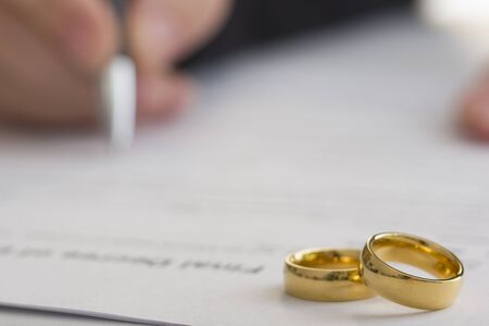 Hands of wife, husband signing decree of divorce, dissolution, canceling marriageの写真素材