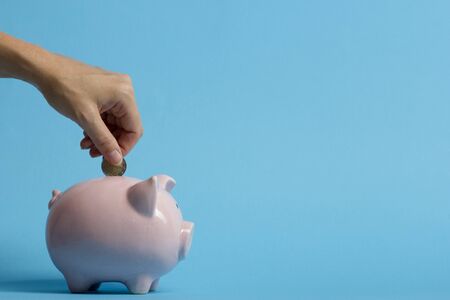 woman hand putting money coin into piggy for saving money wealth and financial concept