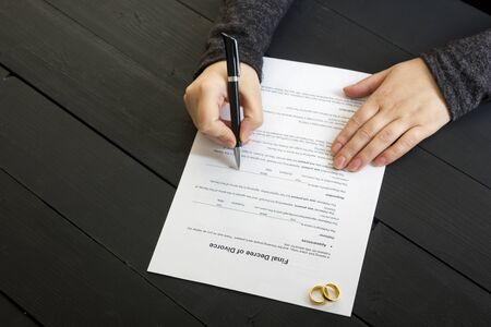 Hands of wife, husband signing decree of divorce, dissolution, canceling marriage, legal separation documents, filing divorce papers or premarital agreement prepared by lawyer. Wedding ringの写真素材