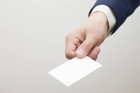Hand holding white business card on white backgroundの写真素材