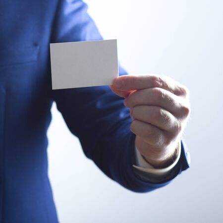 Hand holding white business card on white backgroundの写真素材