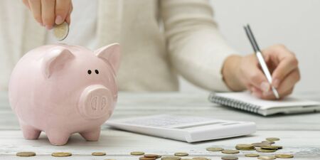 woman hand putting money coin into piggy for saving money wealth and financial conceptの写真素材