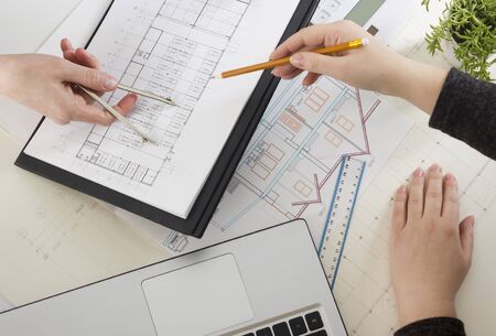 Architects working on blueprint. Architects workplace - architectural project, blueprints, ruler, calculator, laptop and divider compass. Construction concept. Engineering tools.の写真素材