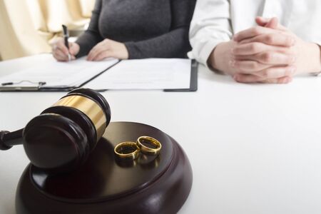 Hands of wife, husband signing decree of divorce, dissolution, canceling marriage, legal separation documents, filing divorce papers or premarital agreement prepared by lawyer. Wedding ringの写真素材