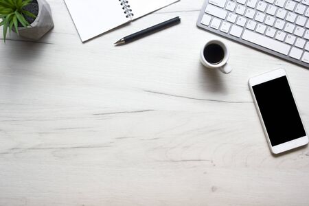 White desk office with laptop, smartphone and other work supplies with cup of coffee. Top view with...