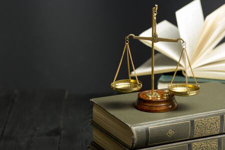 Law concept - Open law book with a wooden judges gavel on table in a courtroom or law enforcement...