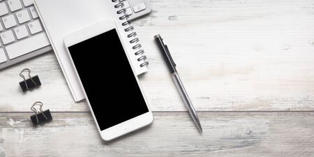 White desk office with laptop, smartphone and other work supplies with cup of coffee. Top view with...