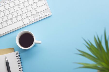 Blue desk office with laptop, smartphone and other work supplies with cup of coffee. Top view with...