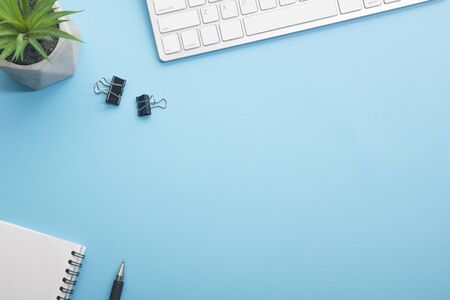 Blue desk office with laptop, smartphone and other work supplies with cup of coffee. Top view with...