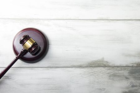 Law concept - Open law book with a wooden judges gavel on table in a courtroom or law enforcement...