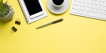 Yellow desk office with laptop, smartphone and other work supplies with cup of coffee. Top view with copy space for input the text. Designer workspace on desk table essential elements on flat lay.の写真素材