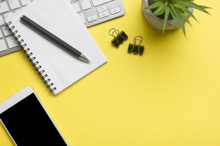 Yellow desk office with laptop, smartphone and other work supplies with cup of coffee. Top view with copy space for input the text. Designer workspace on desk table essential elements on flat lay.の写真素材