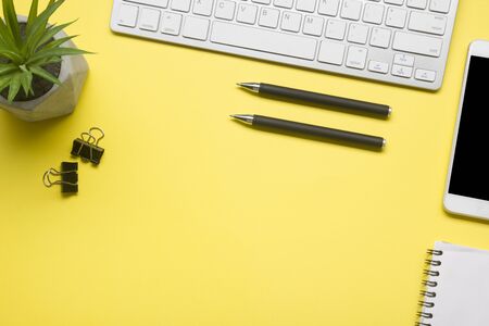 Yellow desk office with laptop, smartphone and other work supplies with cup of coffee. Top view with copy space for input the text. Designer workspace on desk table essential elements on flat lay.の写真素材