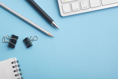Blue desk office with laptop, smartphone and other work supplies with cup of coffee. Top view with...