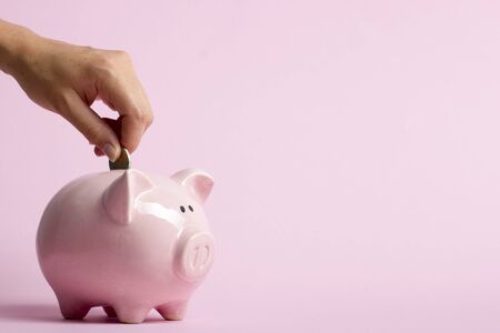 woman hand putting money coin into piggy for saving money wealth and financial concept