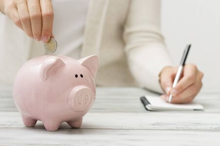 woman hand putting money coin into piggy for saving money wealth and financial concept.の写真素材