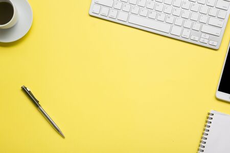 Yellow desk office with laptop, smartphone and other work supplies with cup of coffee. Top view with copy space for input the text. Designer workspace on desk table essential elements on flat lay.の写真素材