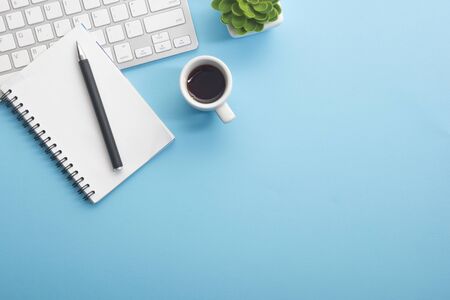 Blue desk office with laptop, smartphone and other work supplies with cup of coffee. Top view with copy space for input the text. Designer workspace on desk table essential elements on flat layの写真素材