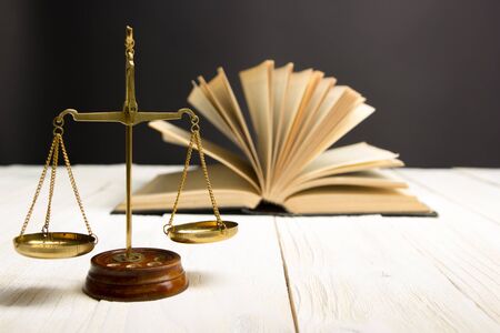 Law concept - Open law book with a wooden judges gavel on table in a courtroom or law enforcement...